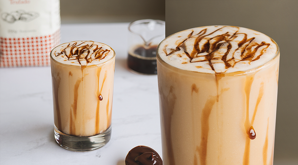 Dois copos de café gelado Baggio em uma mesa, decorados com cobertura de caramelo.